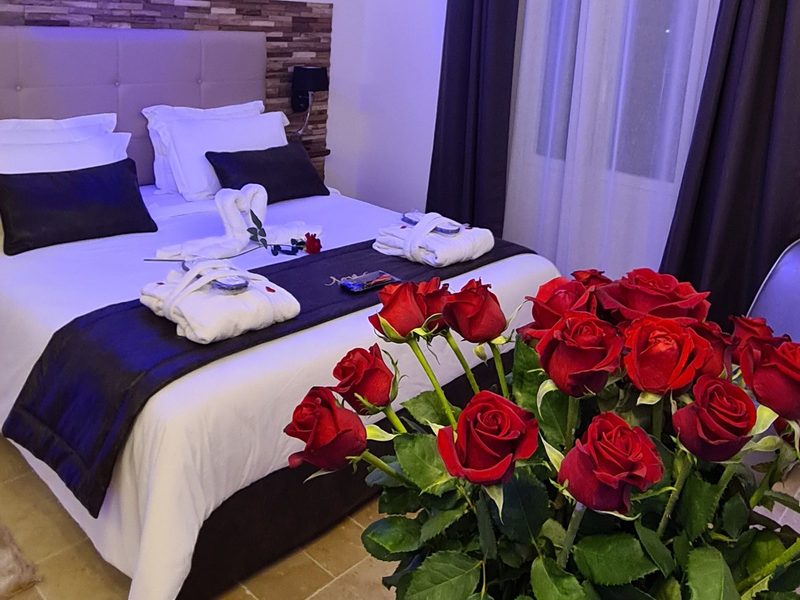 Roses rouges au premier plan et lit préparé pour un séjour en amoureux à La Garçonn’Hyères