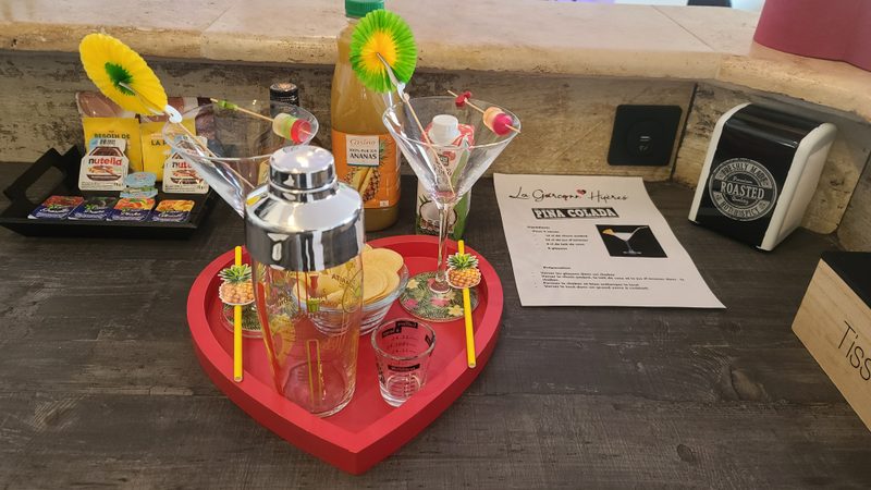 Plateau en cœur avec shaker, deux verres et ingrédients, accompagné de la fiche Piña Colada de La Garçonn’Hyères