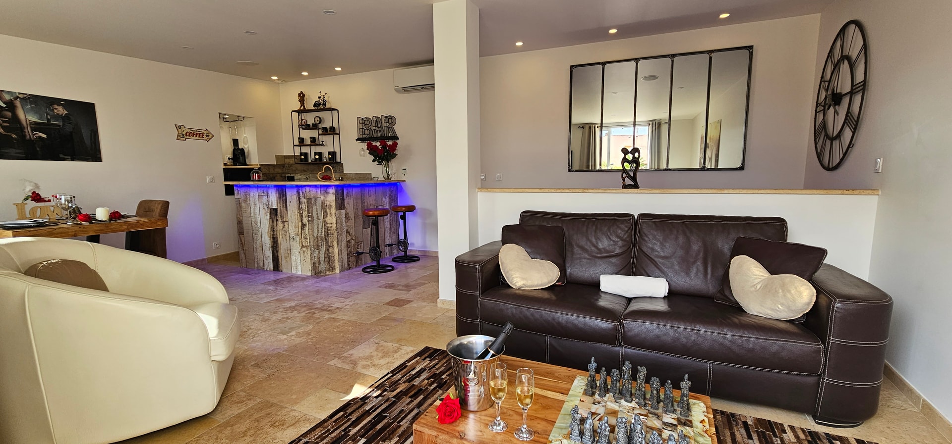 Le salon vu du bar : canapé en cuir, fauteuil arrondi, échiquier et miroirs en verrière au mur